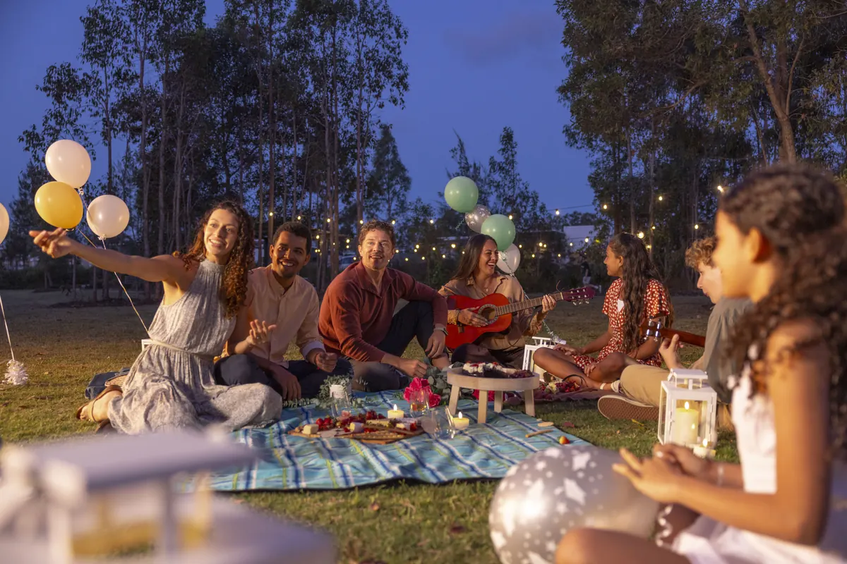 Neighbours at an evening picnic under festoon lights and balloons