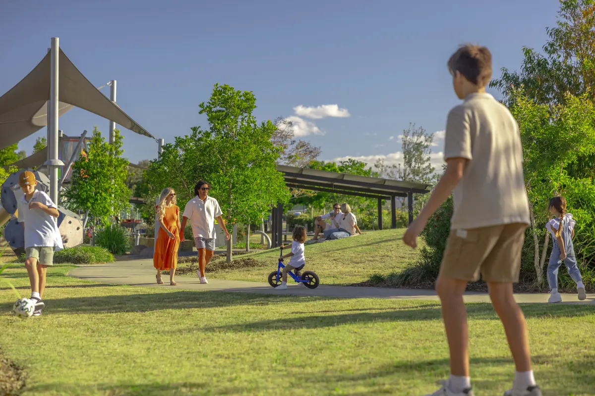 Families playing on the lawn of a park beside a shaded playground